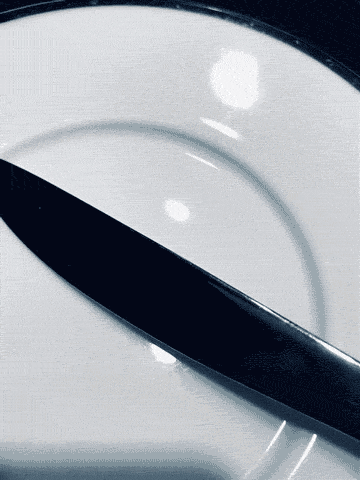 A knife flipping over on a white plate